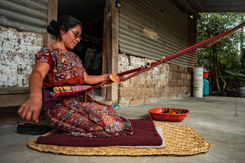 A woman weaves on a new concrete patio in Guatemala
