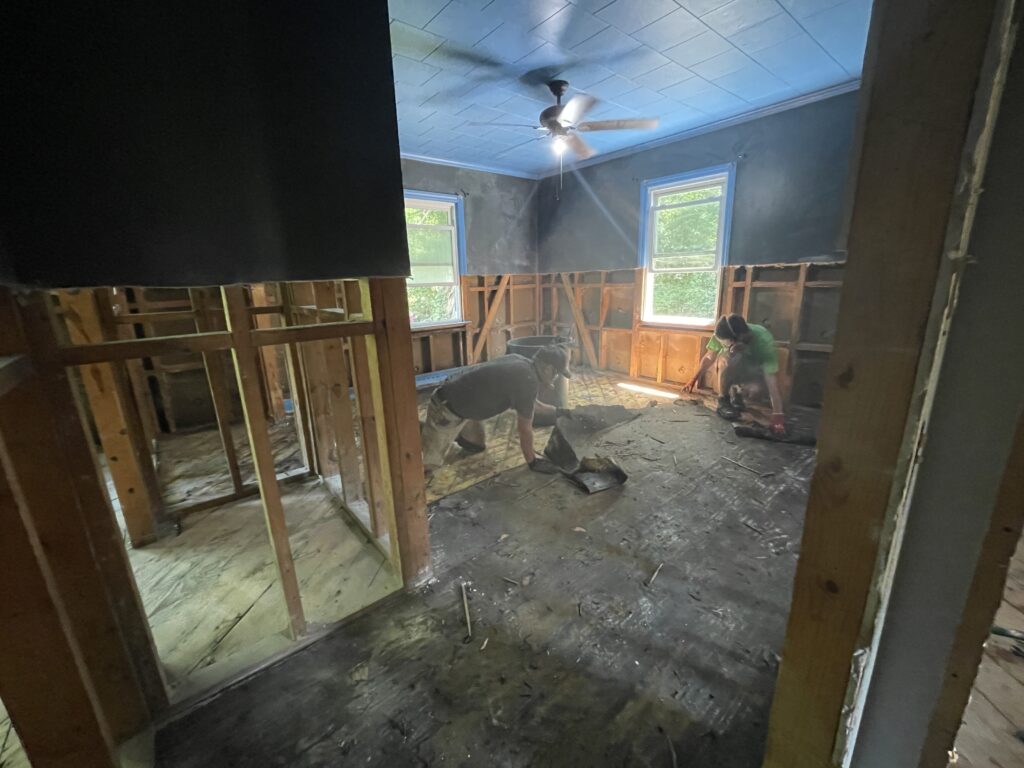 Staff in full-face respirators pulling out flooring from a flooded home in Chapel Hill.