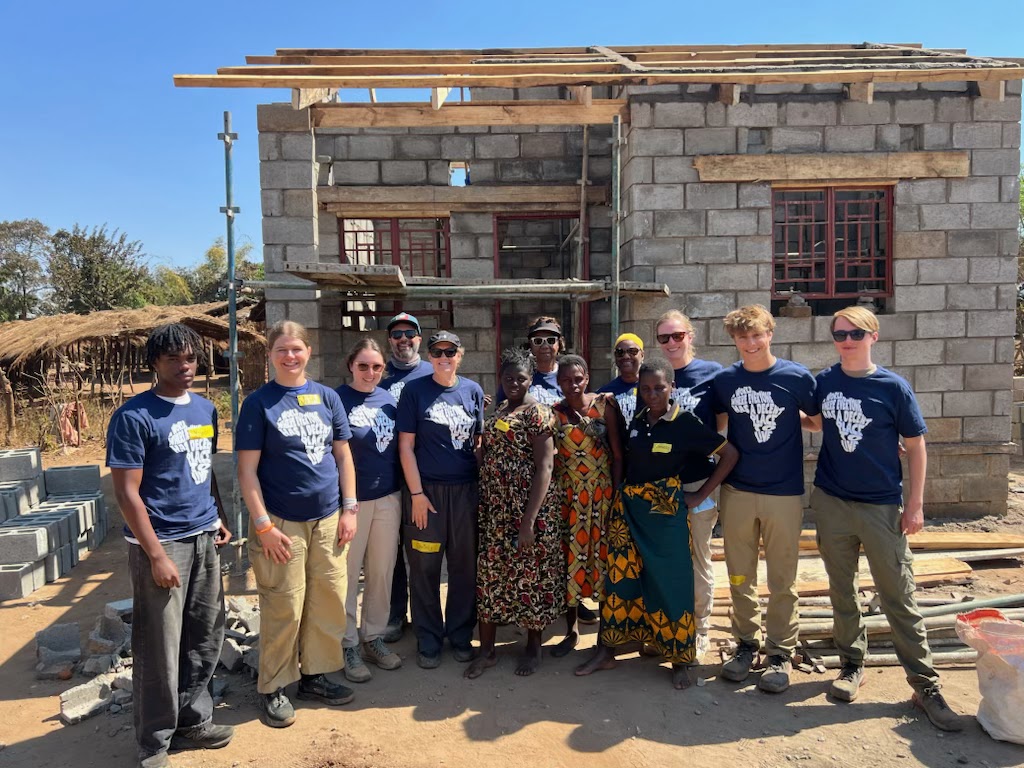 One of two groups of Orange Habitat volunteers poses in front of a home they built in Malawi